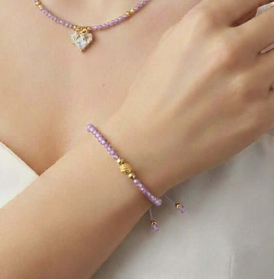 Lazos de Amistad - Pulsera de cristales en brazo con cuentas moradas y detalles dorados.