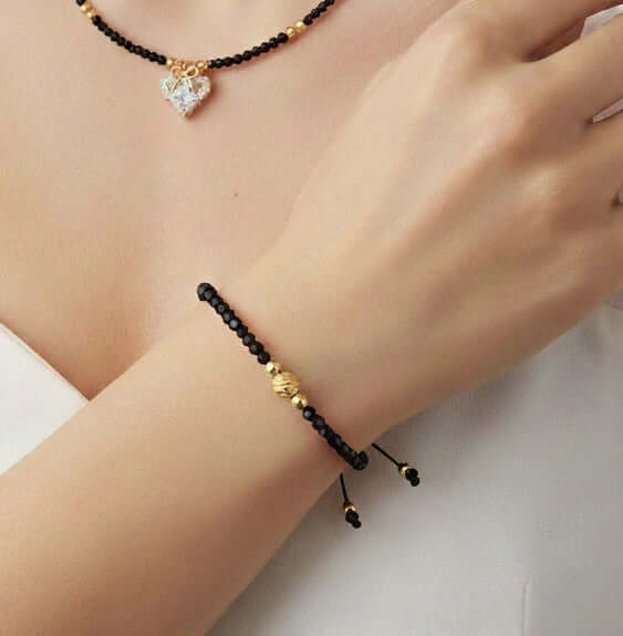 Lazos de Amistad - Pulsera de cristales decorada con cuentas negras y doradas en una muñeca elegante.