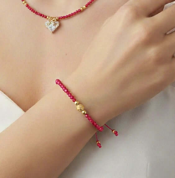 Lazos de Amistad - Pulsera de cristales en una muñeca con cuentas rojas y detalles dorados.